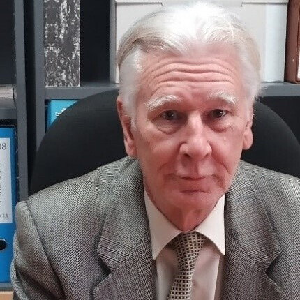 Man with short, grey hair in suit.